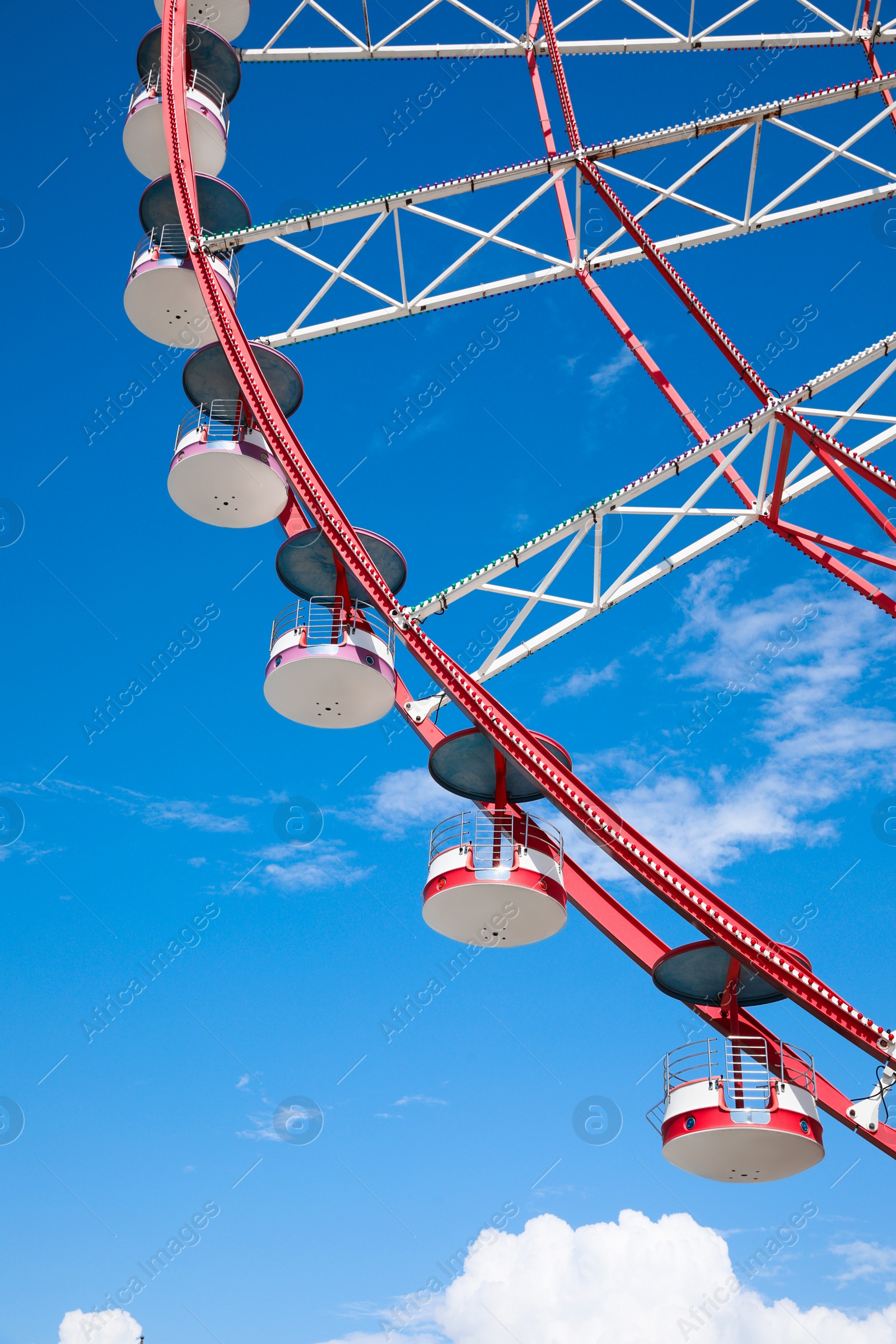 Photo of Beautiful large Ferris wheel against blue sky, low angle view