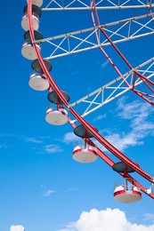 Photo of Beautiful large Ferris wheel against blue sky, low angle view