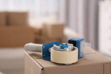 Photo of Dispenser with roll of adhesive tape on box indoors, closeup. Space for text