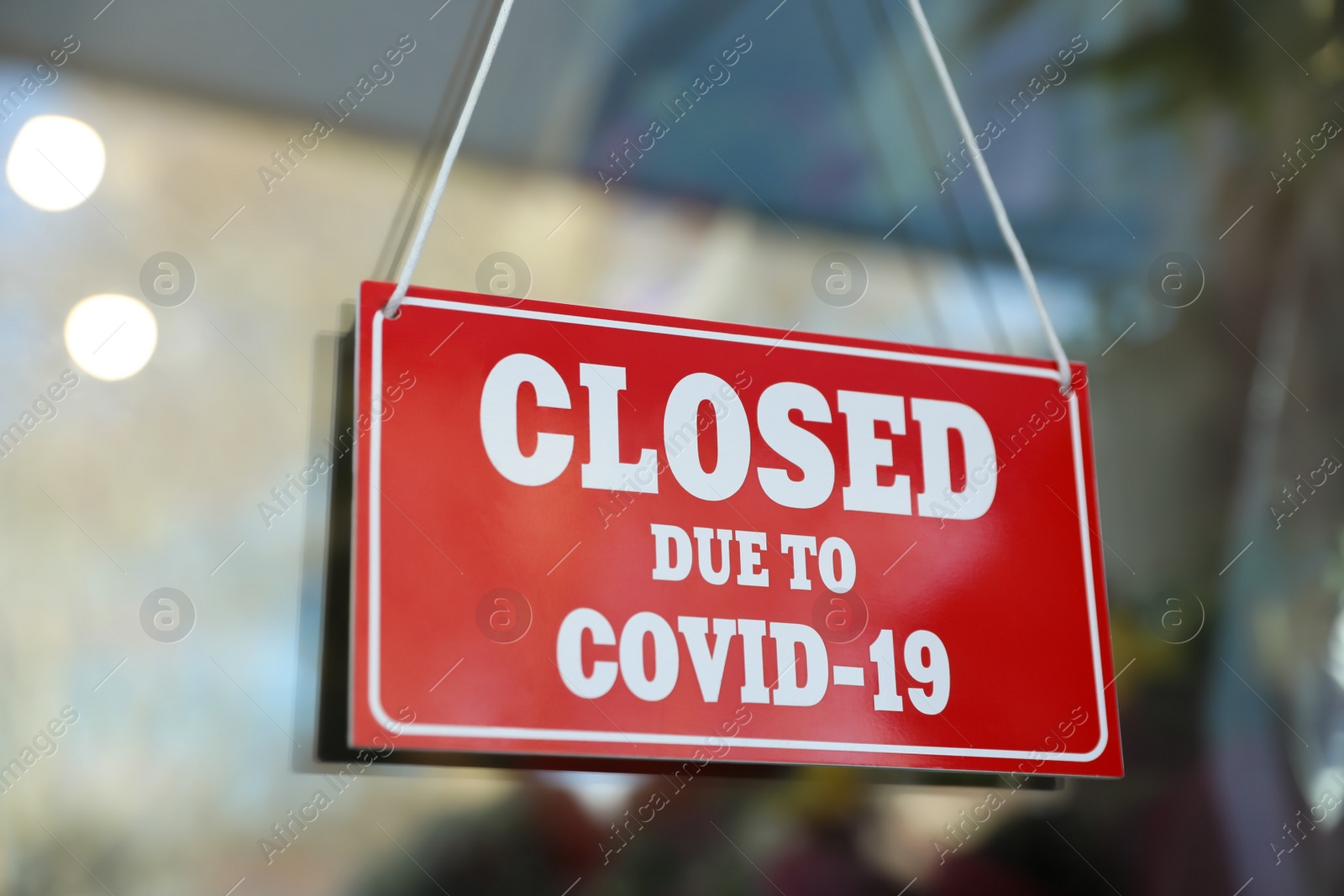 Photo of Red sign with text Closed Due To Covid-19 hanging on glass door. Coronavirus quarantine