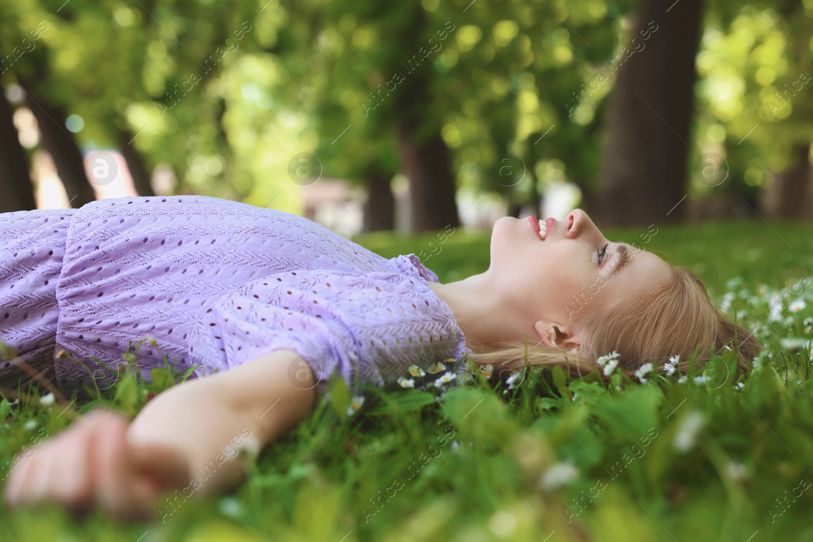 Photo of Beautiful woman lying on green grass in park. Spring sunny day