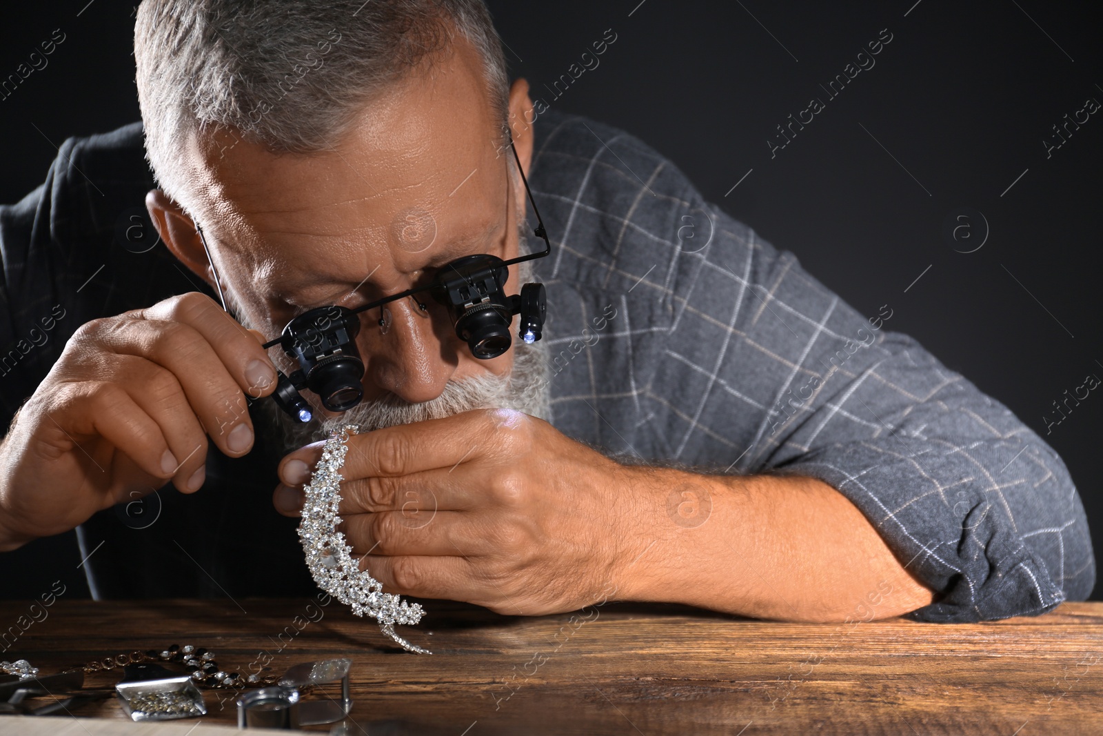 Photo of Male jeweler evaluating diamond necklace in workshop