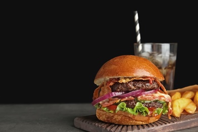 Photo of Tasty burger with bacon and fried potatoes served on table. Space for text