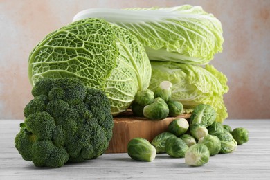 Different types of fresh cabbage on white wooden table