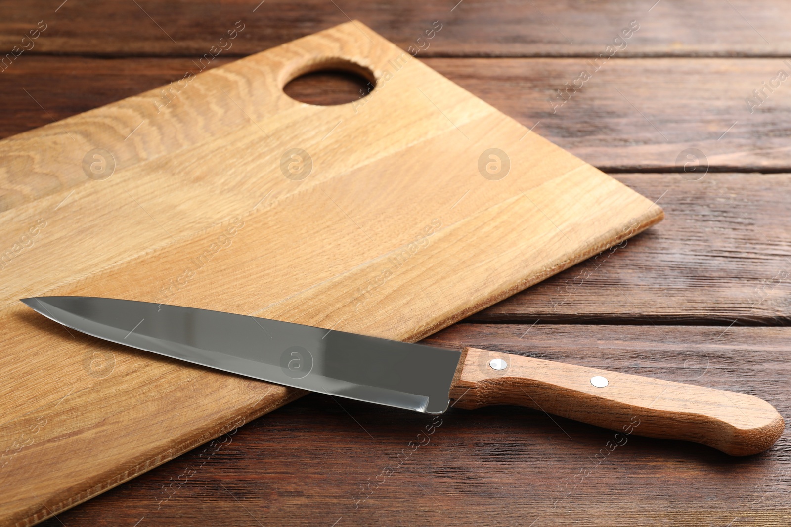 Photo of One sharp knife and board on wooden table, closeup