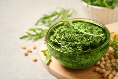 Photo of Bowl of tasty arugula pesto and ingredients on table