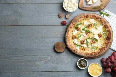 Delicious cheese pizza with walnuts served on grey wooden table, flat lay. Space for text