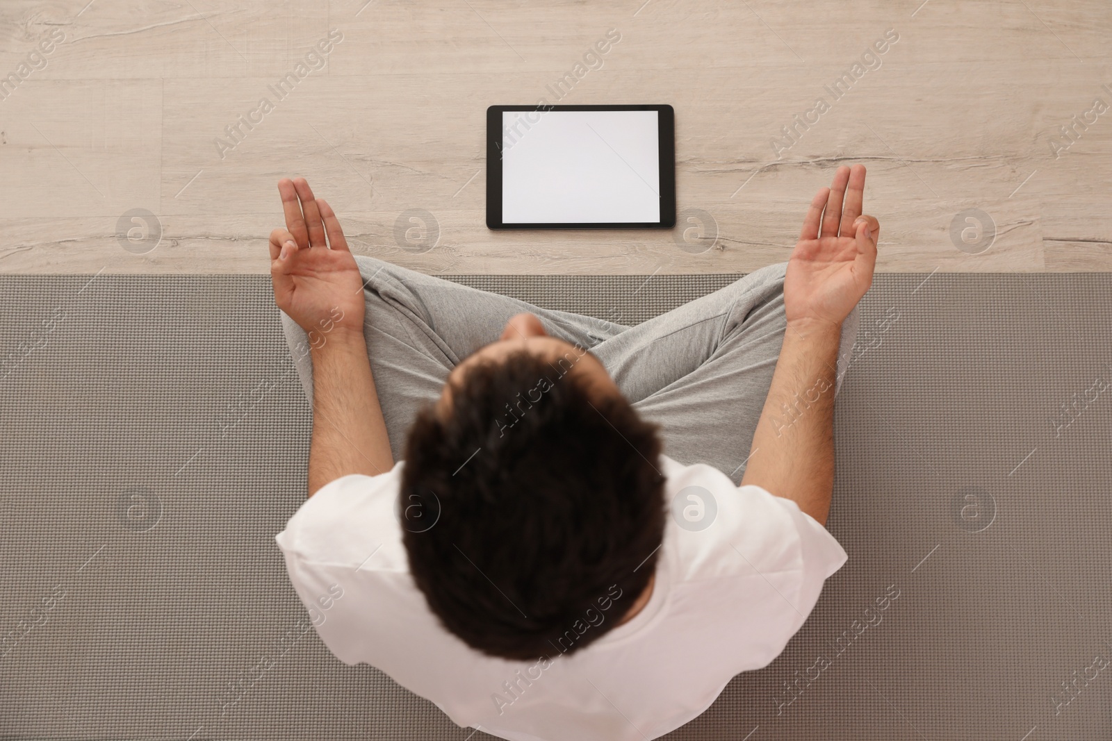 Photo of Man practicing yoga while watching online class at home during coronavirus pandemic, top view. Social distancing