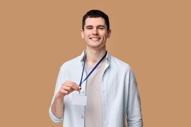 Photo of Smiling man showing empty badge on beige background