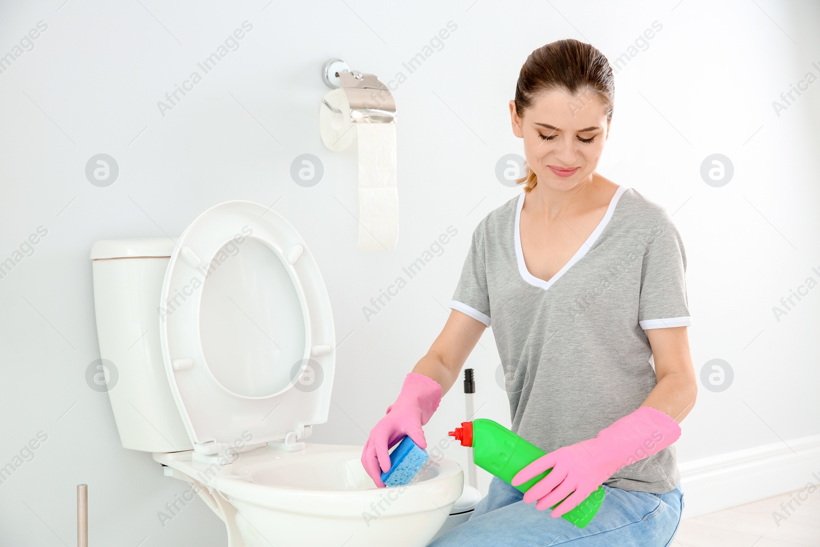 Photo of Woman cleaning toilet bowl in bathroom