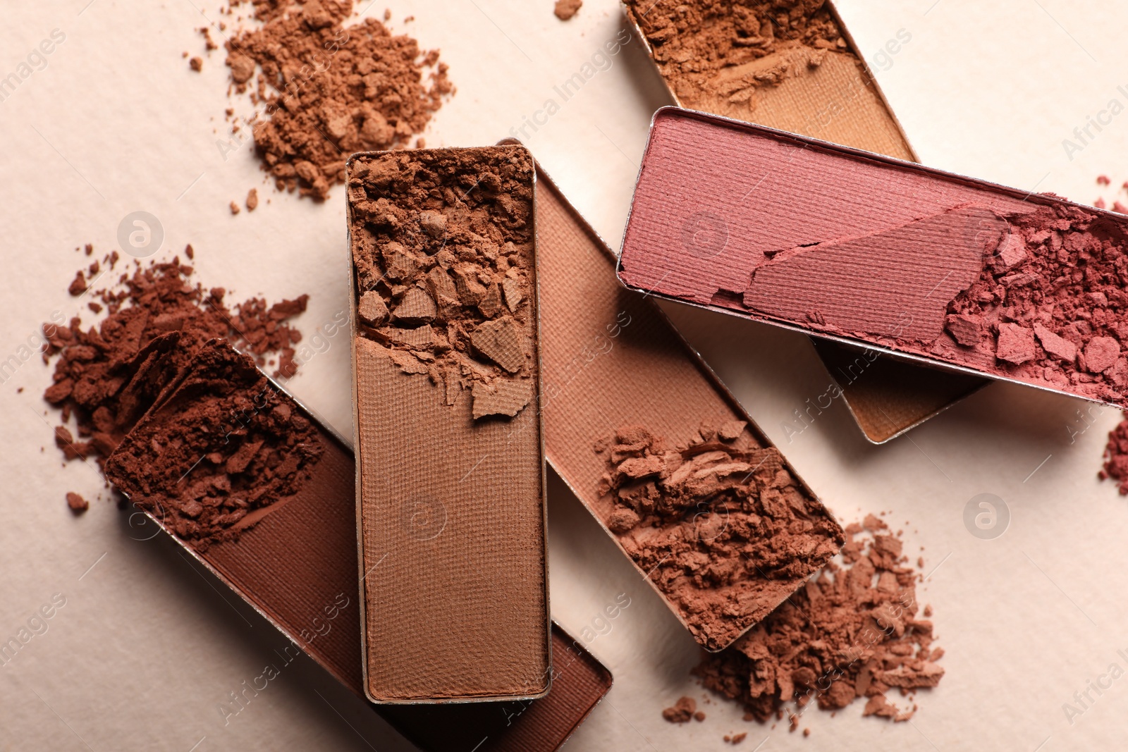 Photo of Different crushed eye shadows on beige background, flat lay