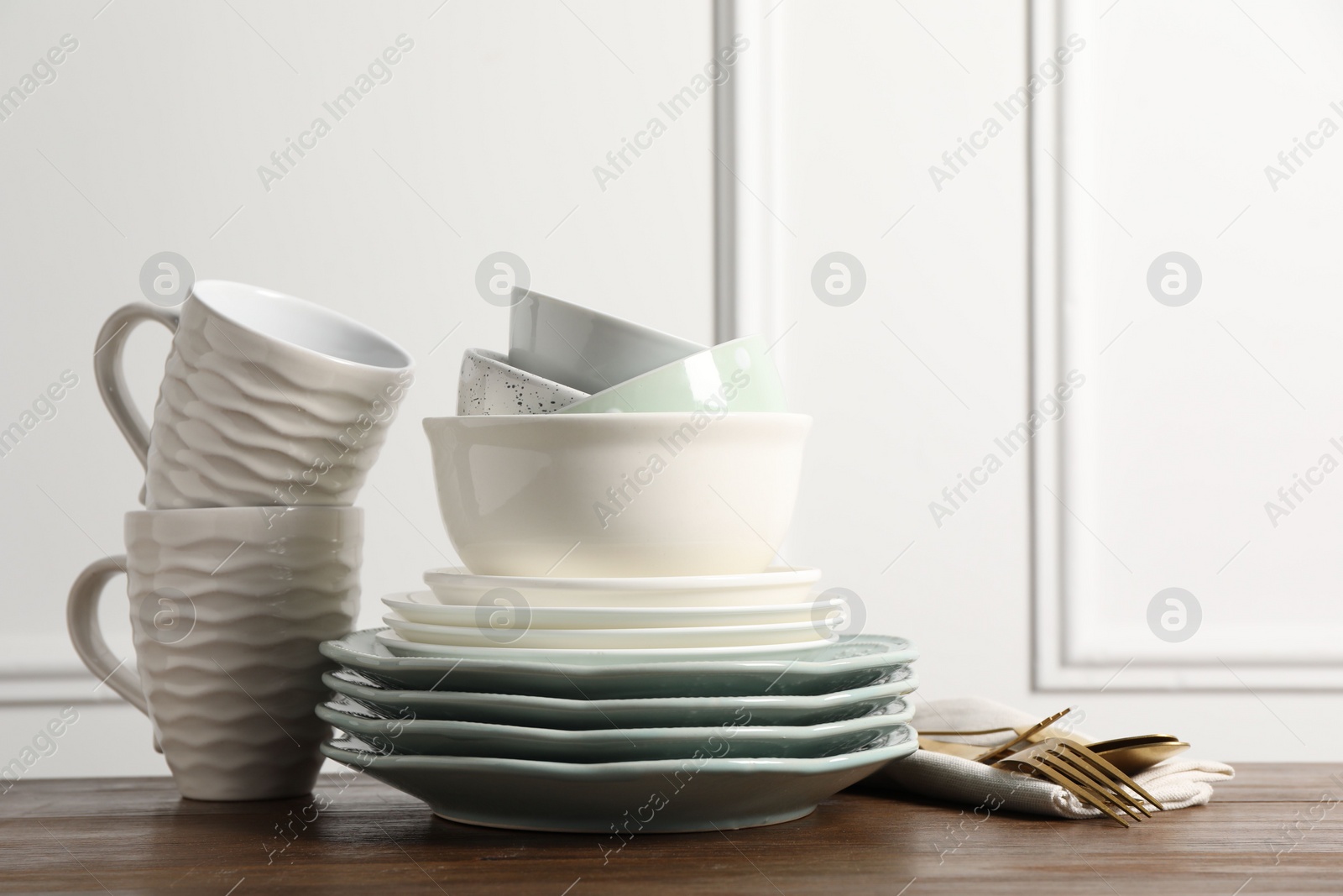 Photo of Beautiful ceramic dishware, cups and cutlery on wooden table