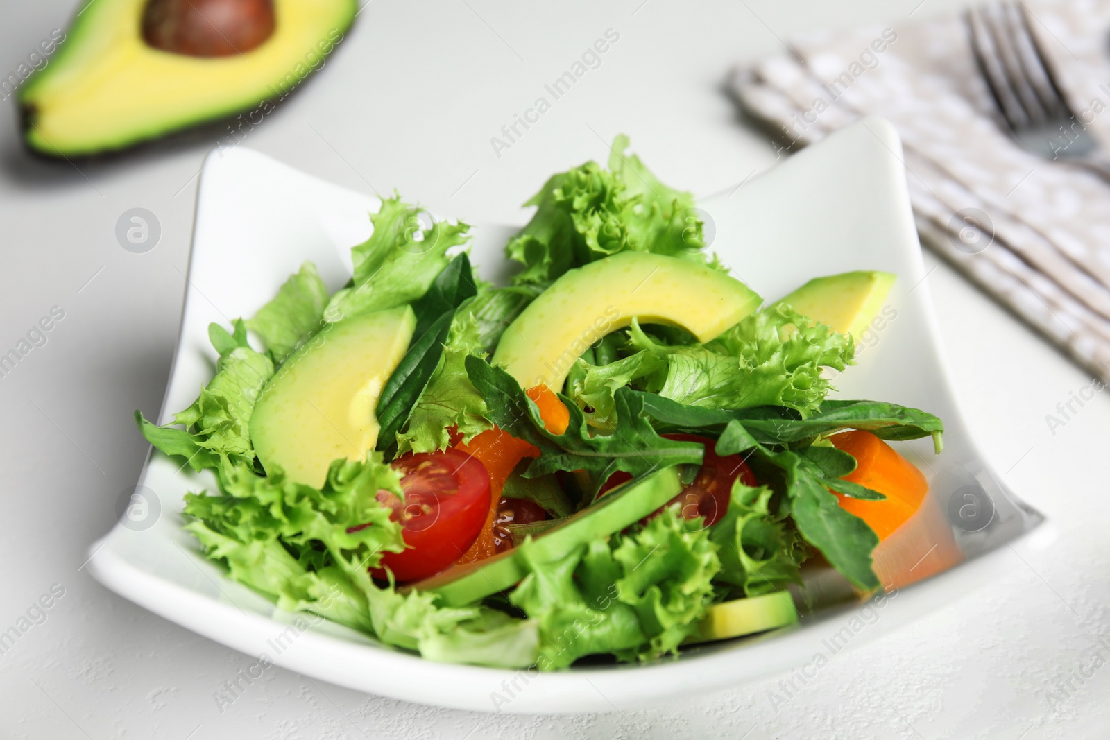 Photo of Delicious avocado salad in bowl on white table