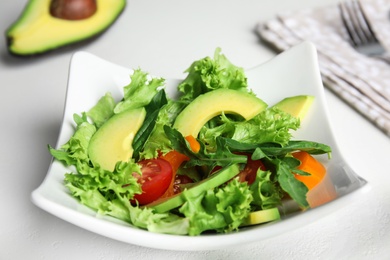 Photo of Delicious avocado salad in bowl on white table