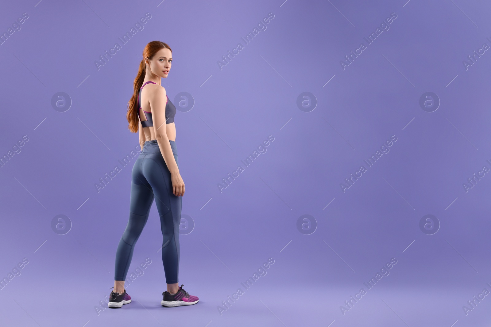 Photo of Young woman wearing sportswear on violet background, space for text