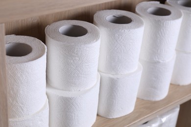 Stacked toilet paper rolls on wooden shelf