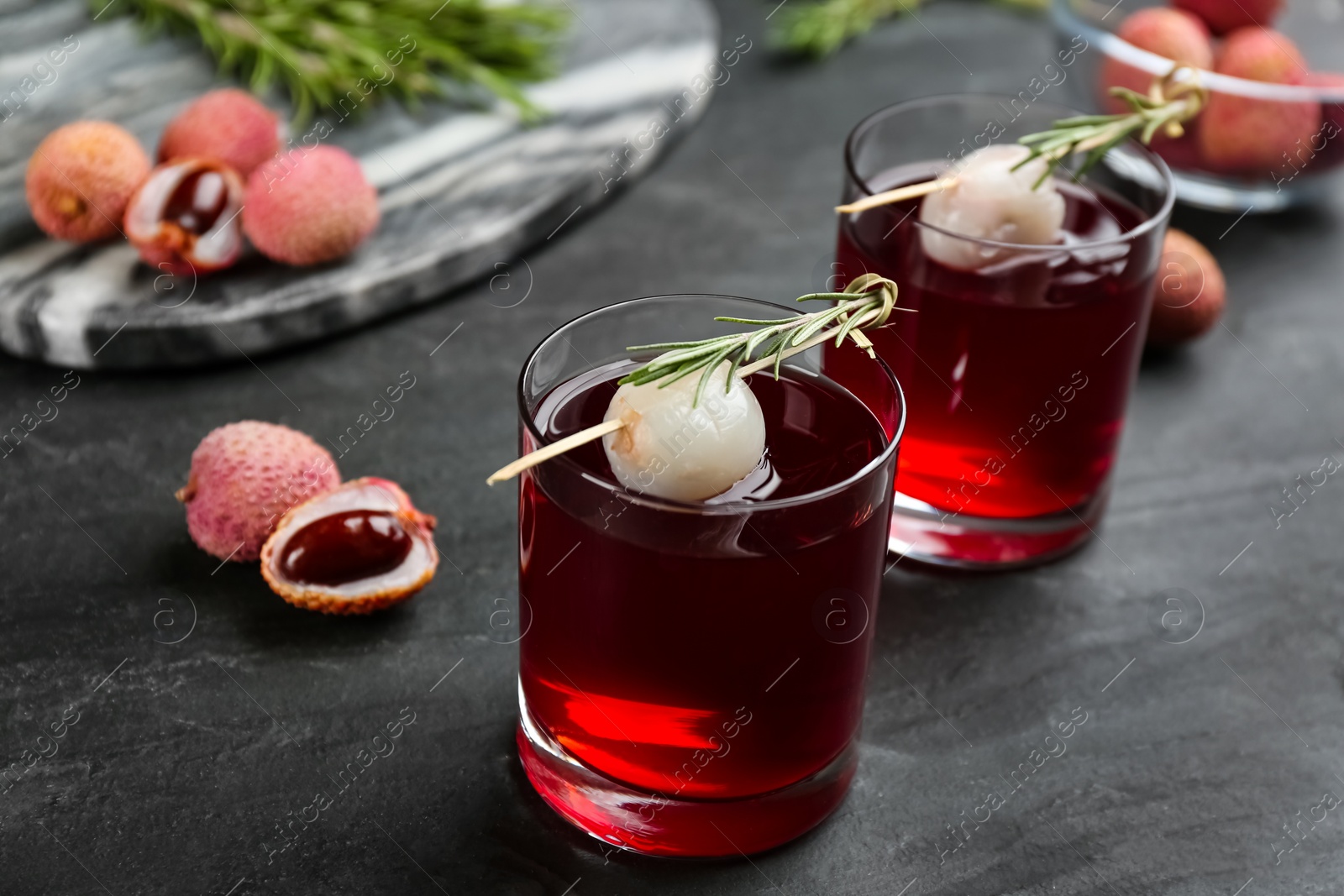 Photo of Delicious lychee cocktails with rosemary and fresh fruits on black table