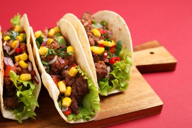 Photo of Delicious tacos with meat and vegetables on red table, closeup