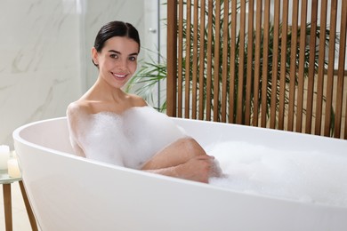 Beautiful young woman taking bubble bath at home