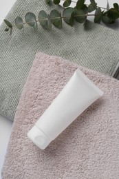 Tube of cream on towels and eucalyptus, above view