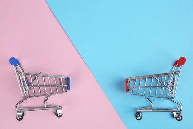 Flat lay composition with empty shopping trolleys on color background. Space for text