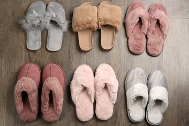 Many different soft slippers on wooden background, flat lay