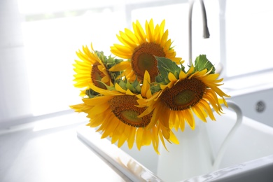 Bouquet of beautiful sunflowers in sink at home