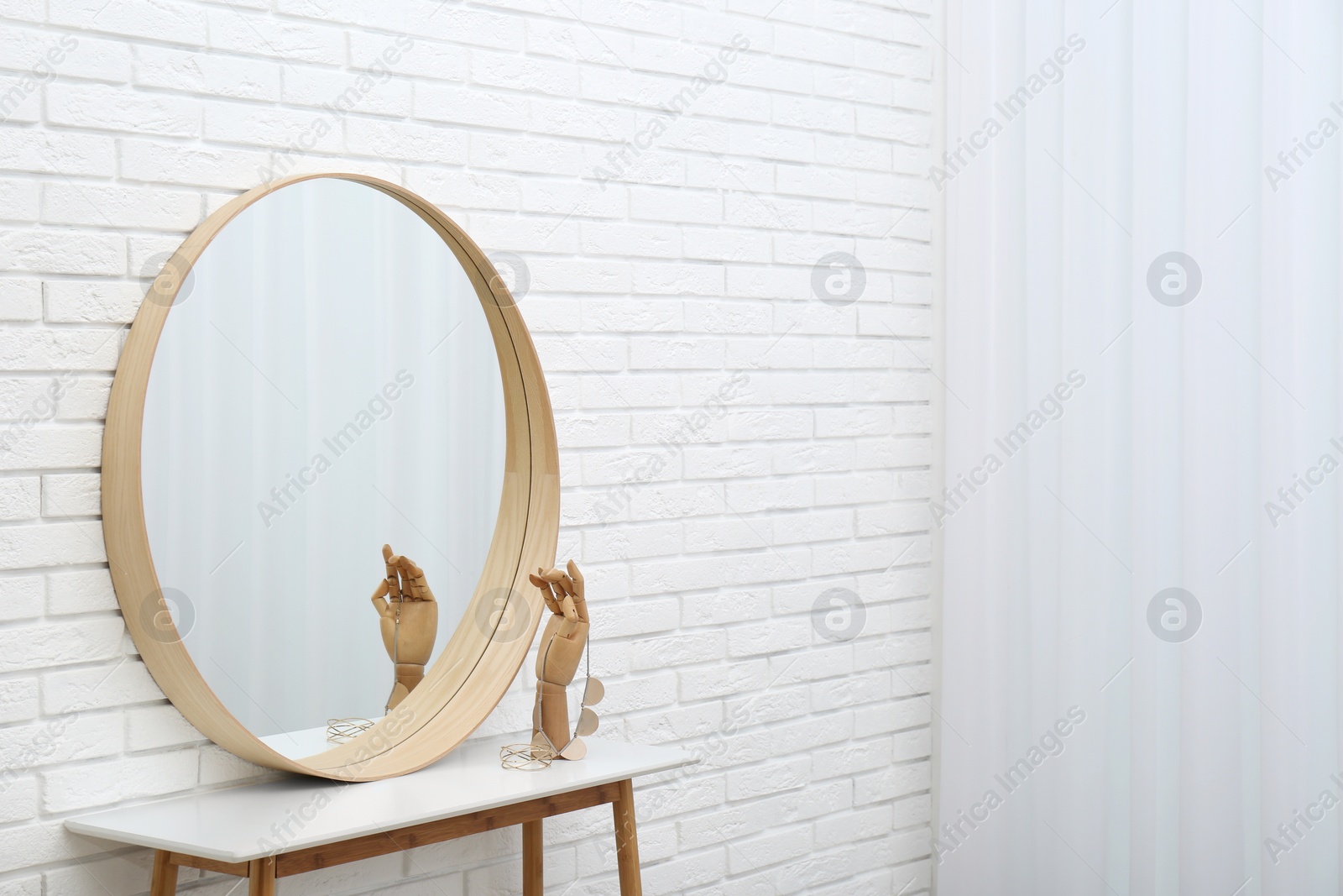 Photo of Round mirror and accessories near white brick wall. Space for text