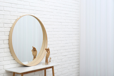 Round mirror and accessories near white brick wall. Space for text