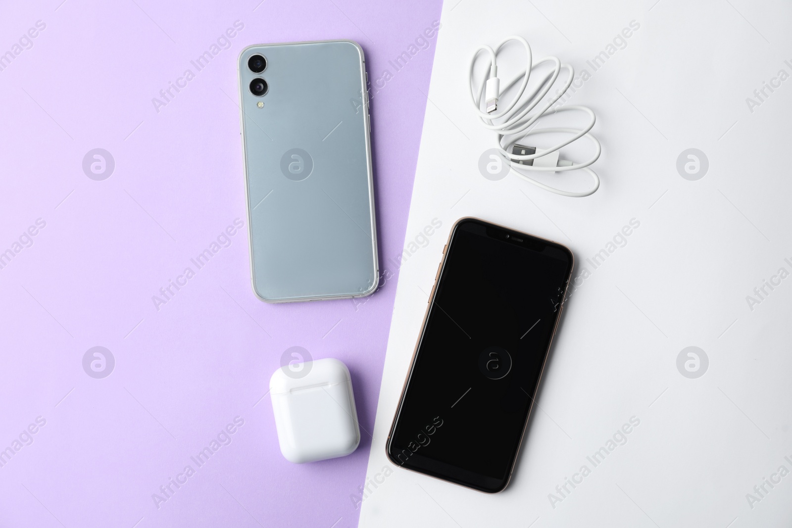 Photo of USB charge cable, wireless earphone case and smartphones on color background, flat lay. Modern technology