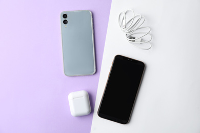 Photo of USB charge cable, wireless earphone case and smartphones on color background, flat lay. Modern technology