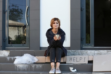 Photo of Poor woman with mug begging and asking for help on city street