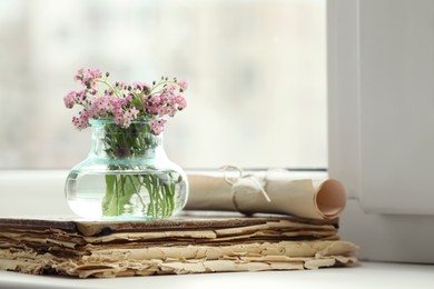Photo of Beautiful Forget-me-not flowers and old book on window sill. Space for text