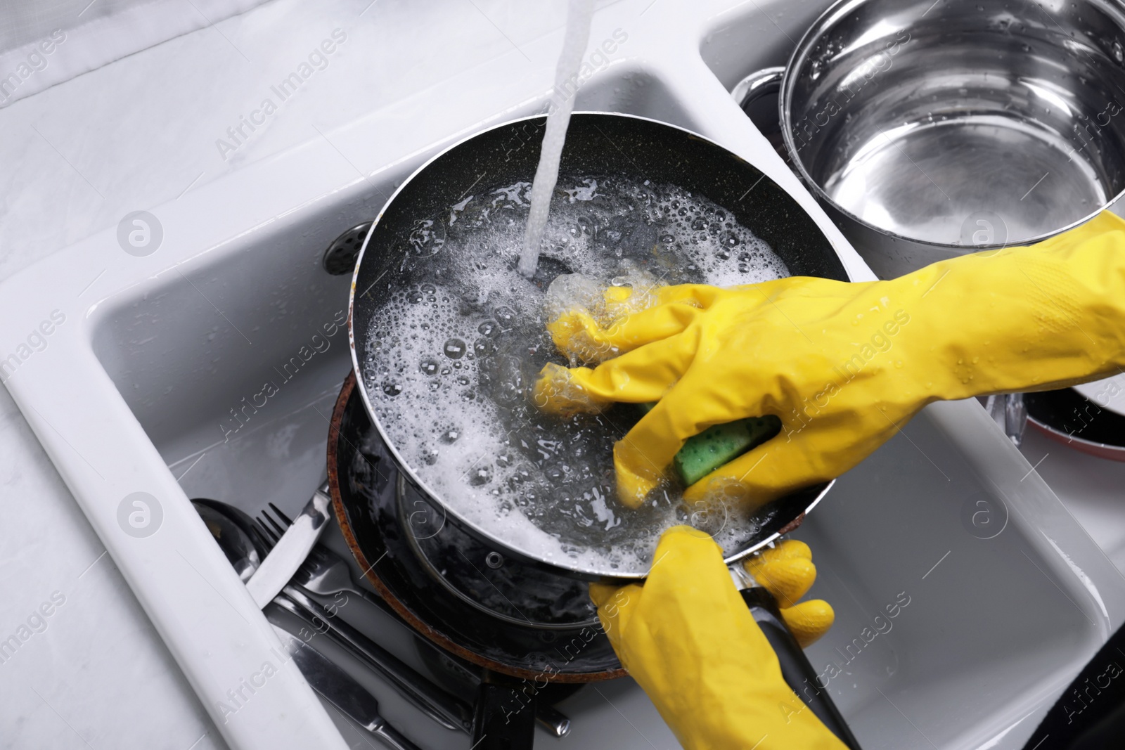 Photo of Woman washing dirty dishes in kitchen sink, closeup