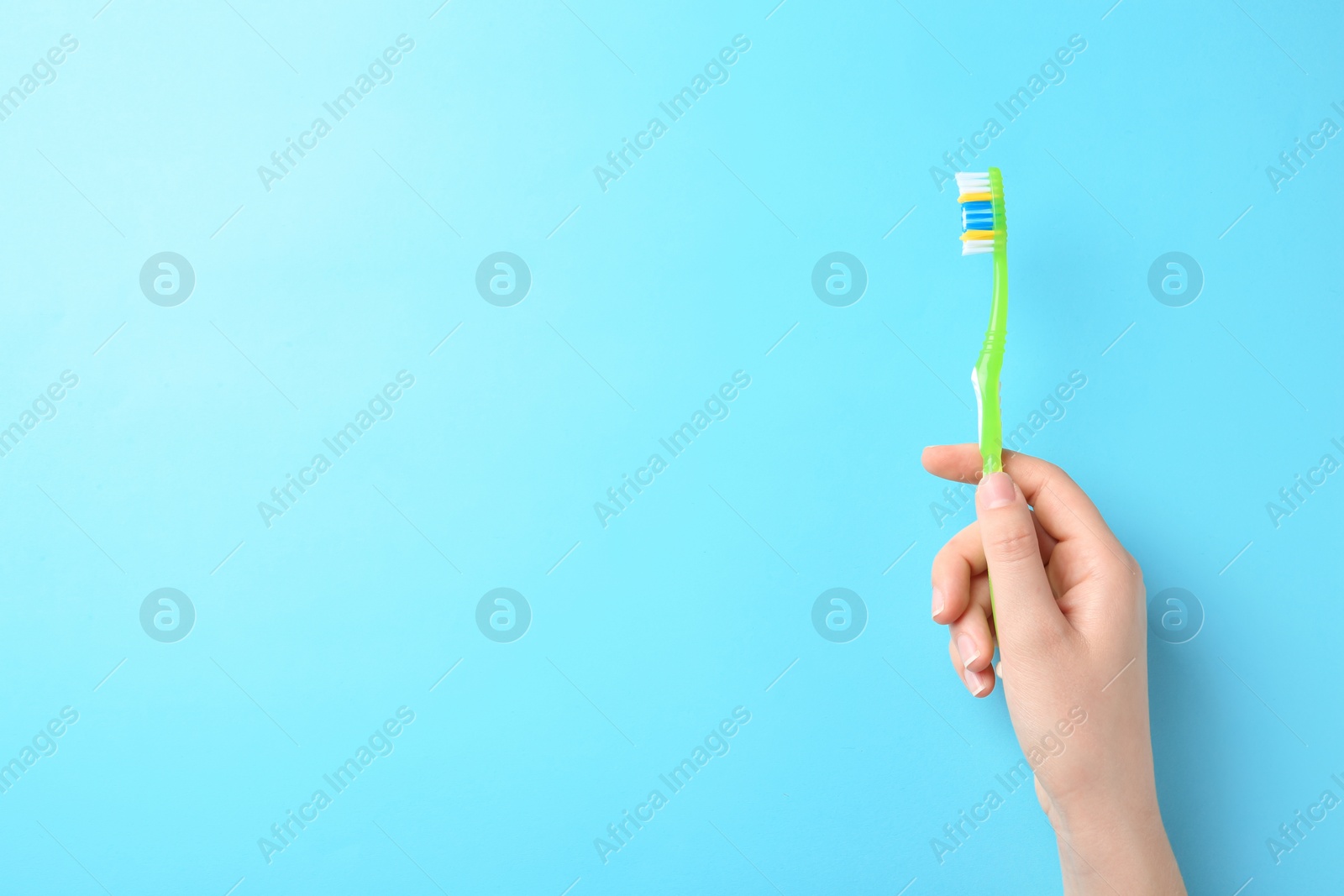 Photo of Woman holding manual toothbrush against color background