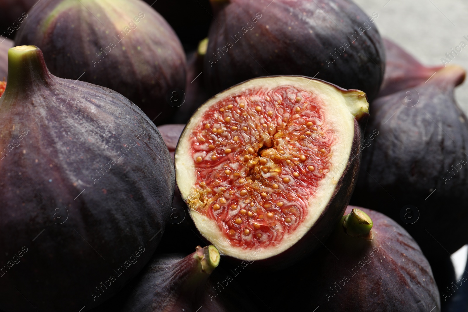 Photo of Whole and cut ripe figs on blurred background, closeup