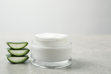 Open jar of cream and cut aloe on grey table. Organic cosmetics