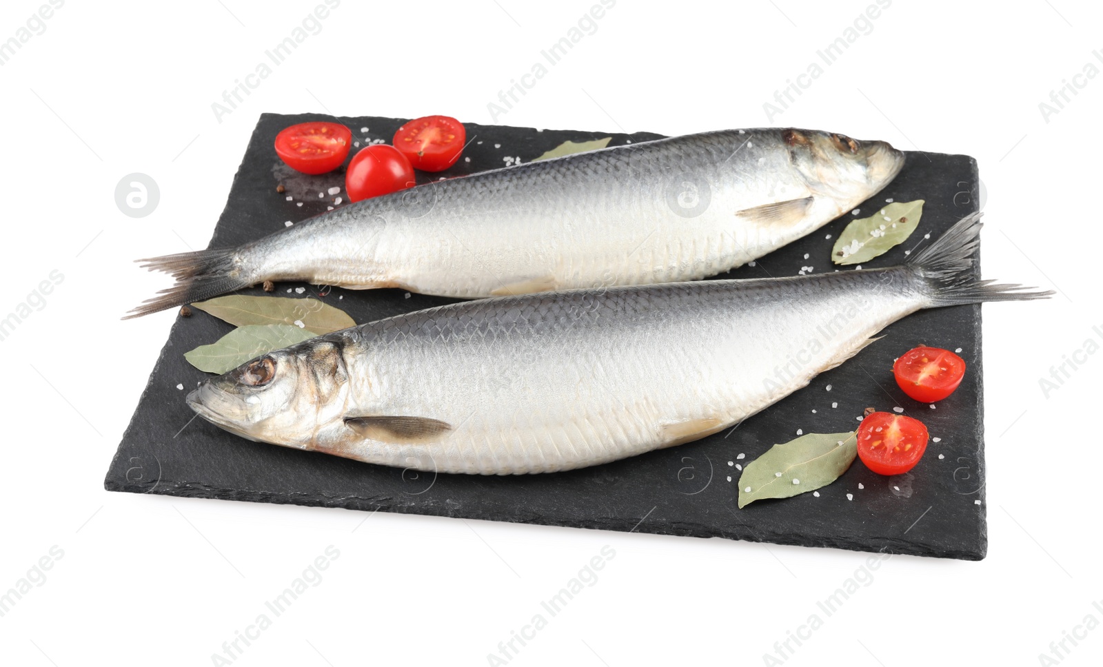 Photo of Slate plate with salted herrings, bay leaves, cherry tomatoes and spices isolated on white