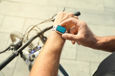 Man using modern smart watch during training outdoors, closeup