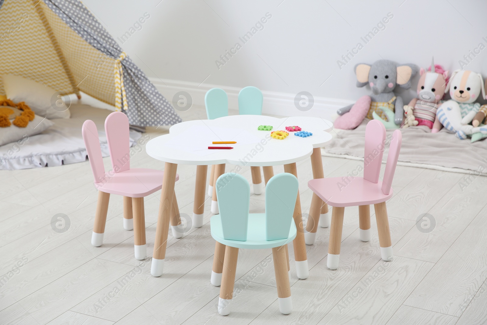 Photo of Little table and chairs with bunny ears in children's room. Interior design