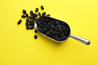 Photo of Scoop with raisins on color background, top view. Dried fruit as healthy snack