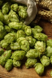 Photo of Fresh hop flowers and wheat ears on wooden table, closeup