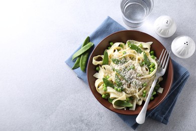 Photo of Delicious pasta with green peas and cheese served on grey table. Space for text