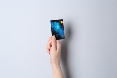 Photo of Woman holding credit card on light grey background, closeup