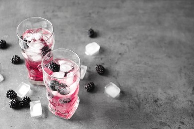 Refreshing blackberry drink with ice on grey table. Space for text