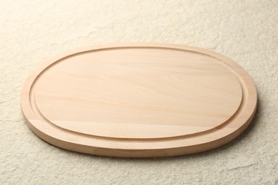 Wooden cutting board on beige table, closeup
