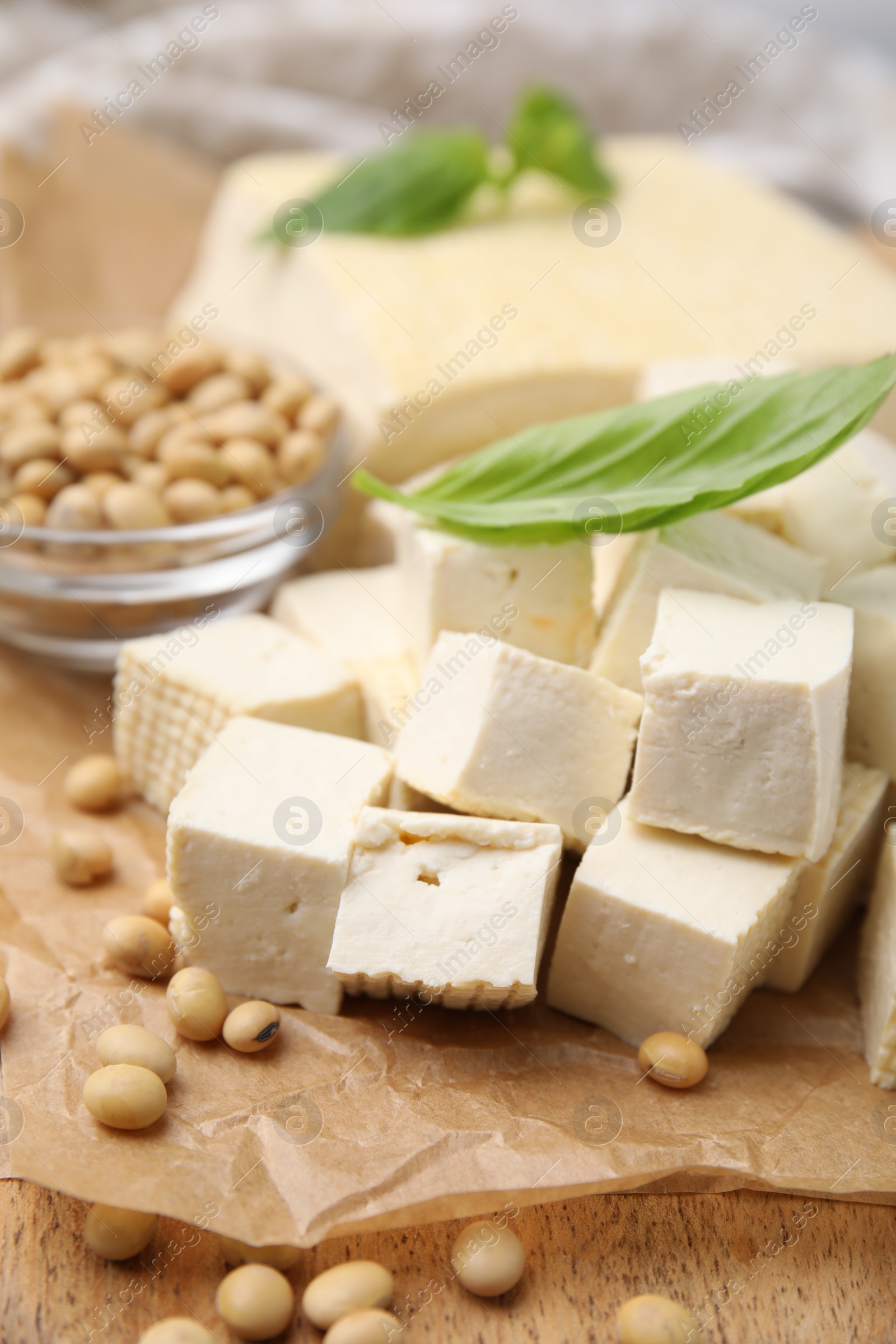 Photo of Delicious tofu cheese, basil and soybeans on wooden board, closeup