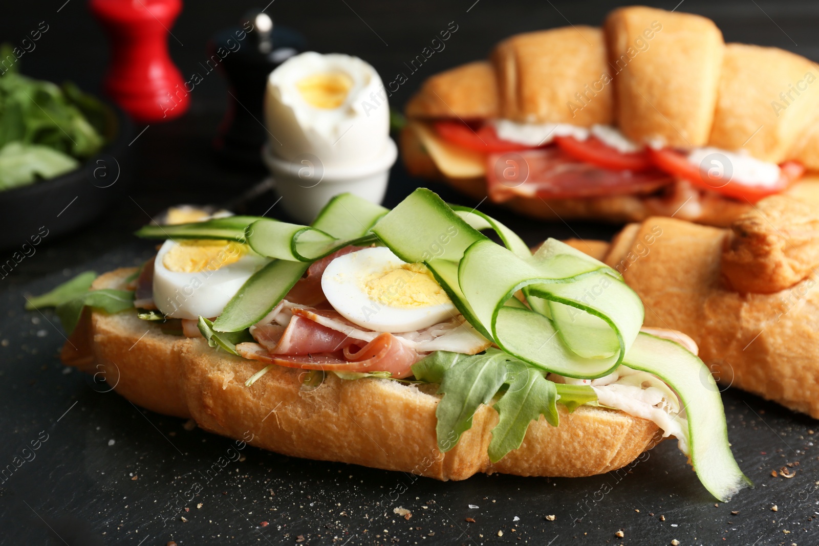 Photo of Tasty croissant sandwich with bacon on table