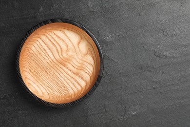 Empty clean wooden plate on black table, top view. Space for text