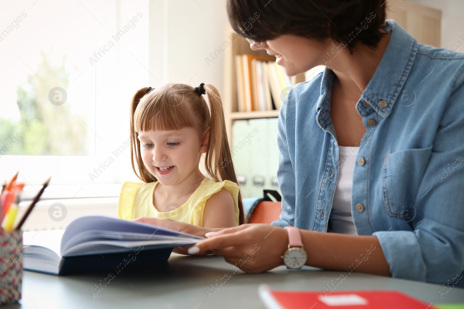 Photo of Female teacher helping child with assignment at school